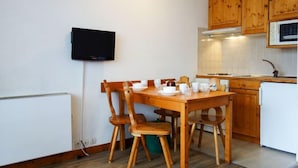 A compact kitchen with wooden cabinets, a white countertop, and a built-in microwave. - Home Club (Lavachet) by Interhome (Tignes)