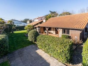 Une maison à deux étages, avec un toit en tuiles, un porche abrité et un jardin bien entretenu.