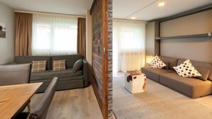 A modern living room with two sofas, a wooden coffee table, and a stone accent wall. - Grillon by Interhome (Zermatt)
