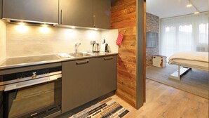A modern kitchen with a built-in oven, a sink, and a wooden accent wall. - Grillon by Interhome (Zermatt)