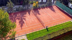 A tennis court surrounded by trees and a building.