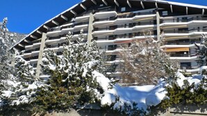 A multi-story hotel with balconies, surrounded by snow-covered trees.