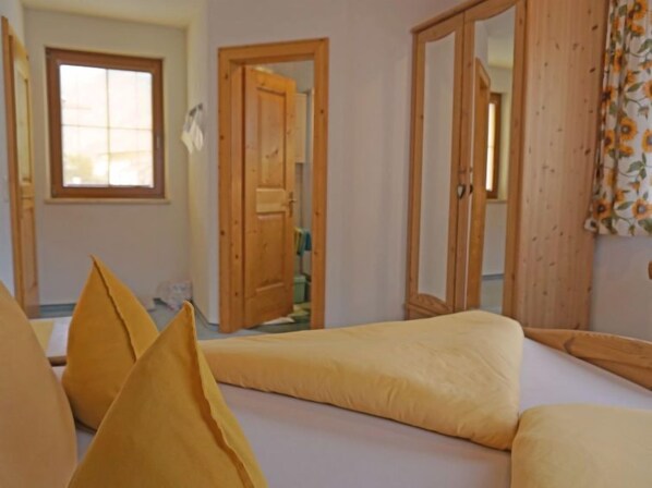 A room with two beds, wooden doors, a window, and a mirror. - Christina by Interhome (Pettneu am Arlberg)