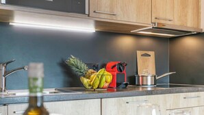 Una cocina moderna con armarios de madera, un fregadero de acero inoxidable y un frutero con plátanos, piña y manzanas.