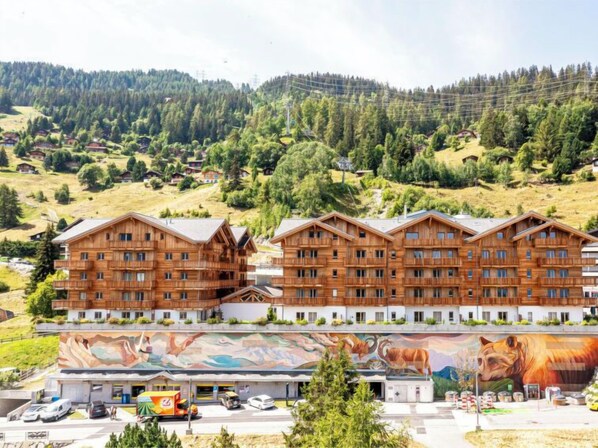 Ein mehrstöckiges Holzhaus mit Balkonen, eingebettet in eine gebirgige Landschaft.
