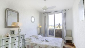 A bedroom with a bed, dresser, mirror, and a view of the outdoors through a window. - Galiote by Interhome (Cogolin)