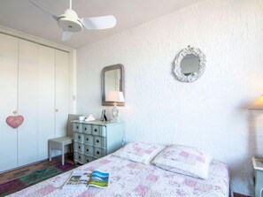 A bedroom with a bed, dresser, mirror, and ceiling fan.