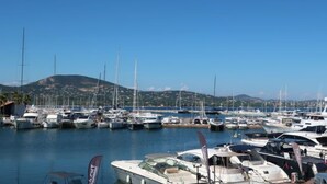 A marina with various boats docked, a clear sky, and a hilly landscape in the background. - Galiote by Interhome (Cogolin)