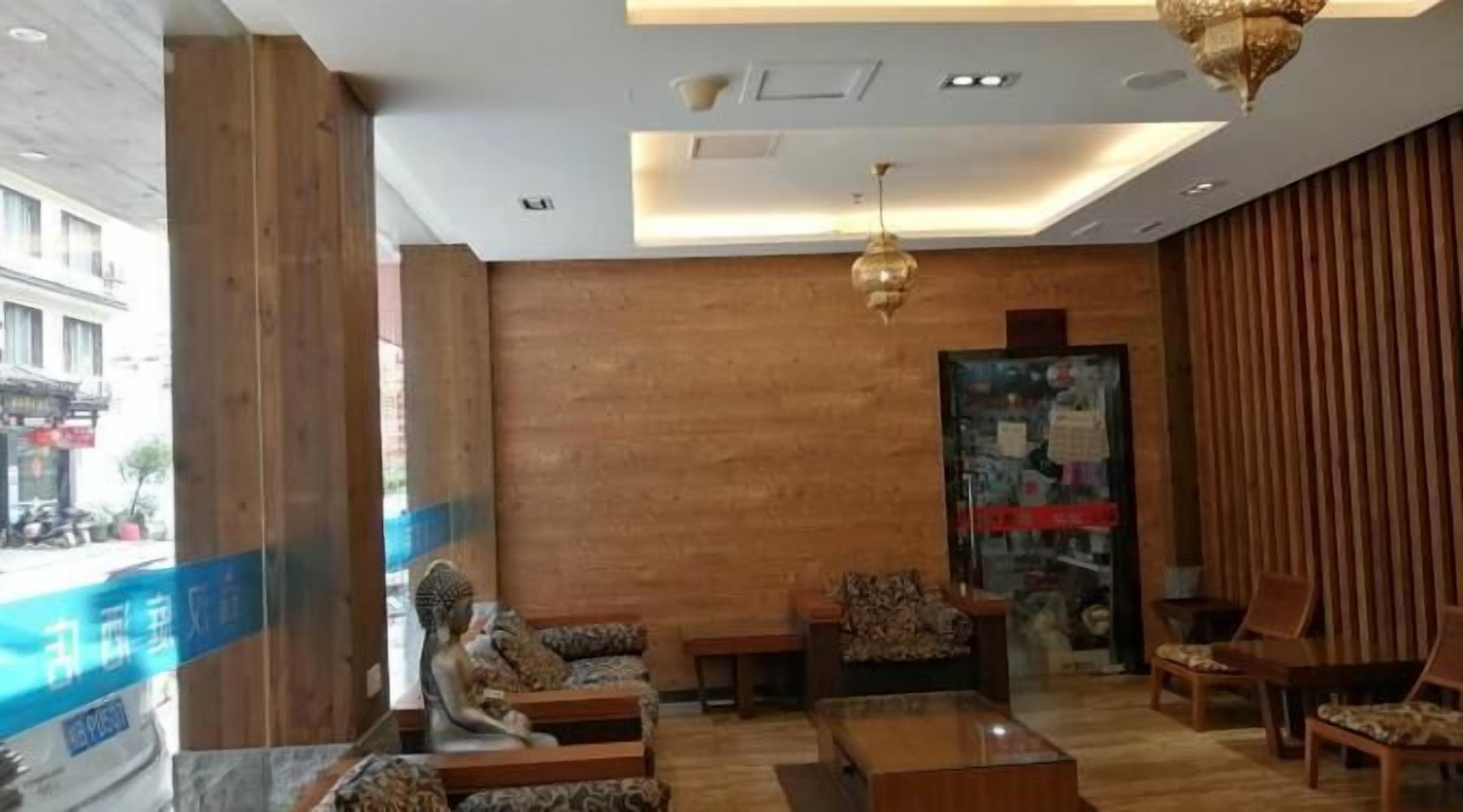 A modern lobby with wooden walls, a glass door entrance, and a seating area with patterned sofas and a coffee table.