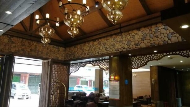 A stone-walled interior with a wooden ceiling and hanging lamps. There is a seating area with a view of the street outside. - Hanting Express Yangshuo West Street (Guilin)