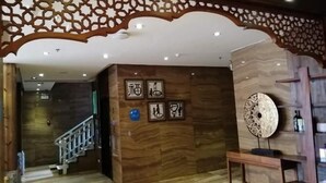 A lobby with a wooden staircase, a decorative ceiling, and framed wall art. - Hanting Express Yangshuo West Street (Guilin)