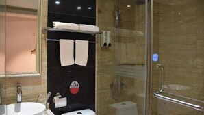 A modern bathroom with a glass shower enclosure, a white sink, and a towel rack with two towels. - Hanting Express Yangshuo West Street (Guilin)