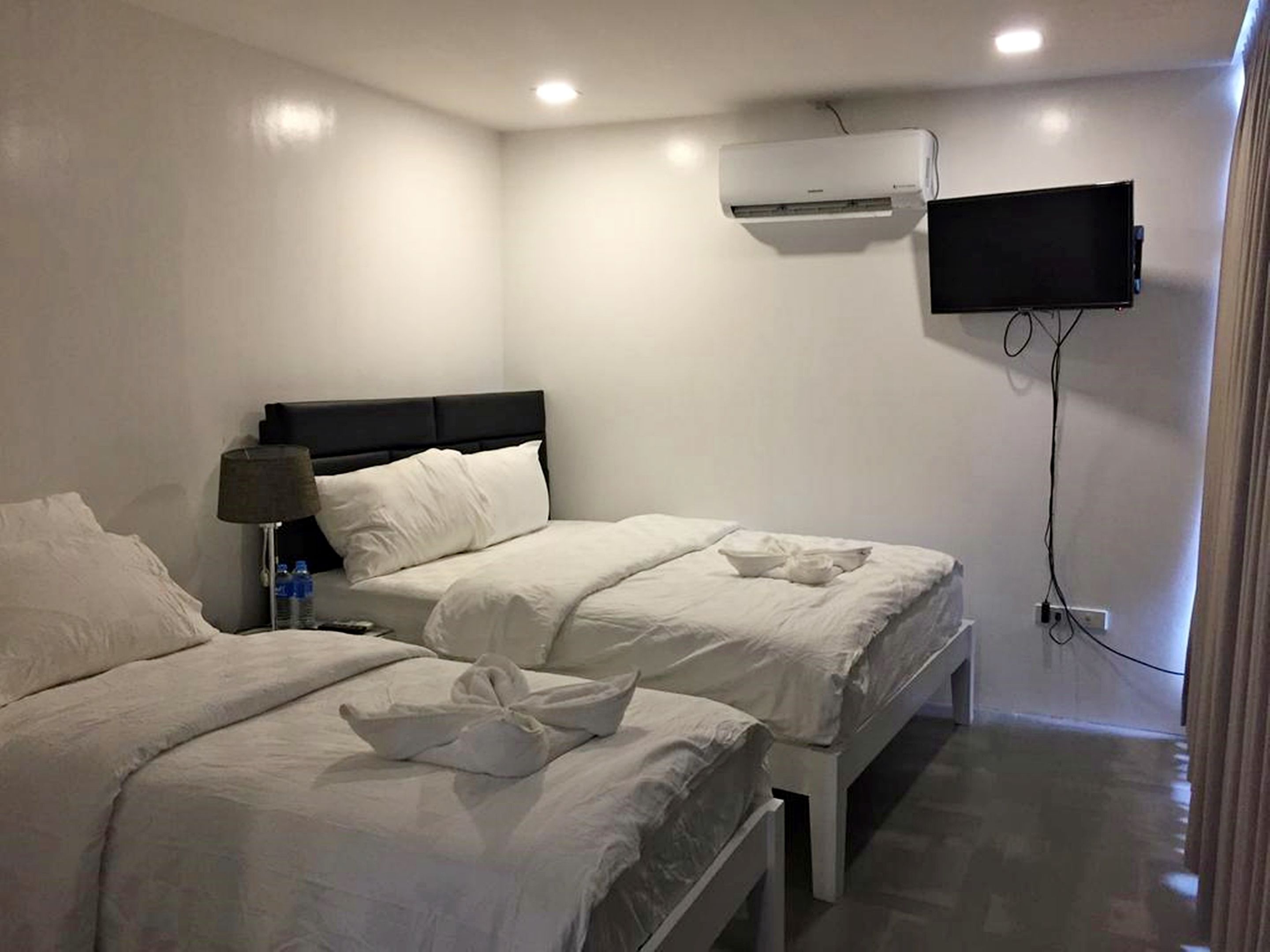 Une chambre d’hôtel avec deux lits, un téléviseur à écran plat fixé au mur et un appareil de climatisation.