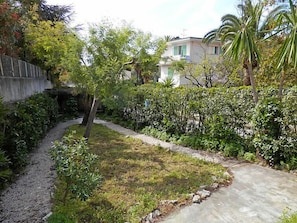 A garden with a gravel path, various shrubs, and a small tree.
