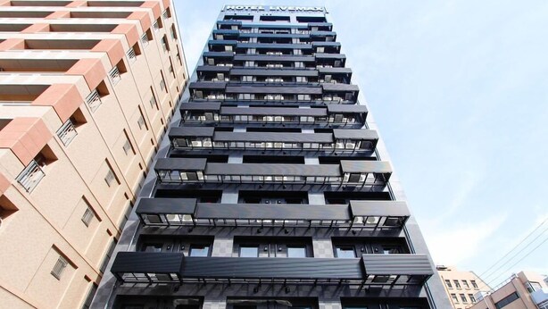Un edifici d'hotel modern amb múltiples balcons i un senyal ben visible que diu "HOTEL L'VEMAX".