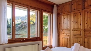 A bedroom with a bed, a window, and wooden paneling.