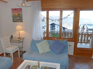 Et hyggeligt værelse med seng, stol, bord med lampe og et billede på væggen.