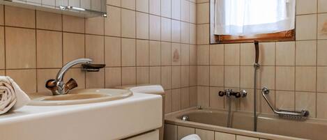 Un baño con lavamanos, inodoro y bañera.