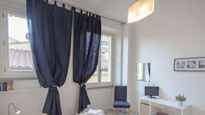 Een hotelkamer met een bed, bureau, stoel, televisie en een raam met gordijnen.