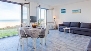 A modern living room with a large glass door leading to a balcony overlooking a beach. - Les Caravelles by Interhome (Cabourg)
