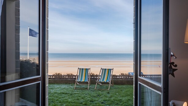 A balcony with two striped chairs facing a beach. - Les Caravelles by Interhome (Cabourg)