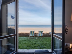 Un balcon avec deux chaises à rayures donnant sur une plage.