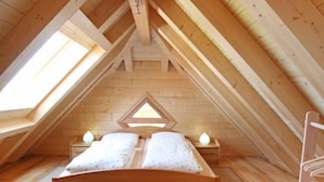 A wooden attic bedroom with a sloped ceiling, a bed, two bedside tables, and a skylight. - Apartment Lärche by Interhome (Grosserlach)