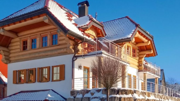 A log cabin with a stone foundation, wooden balconies, and a snow-covered roof. - Apartment Lärche by Interhome (Grosserlach)