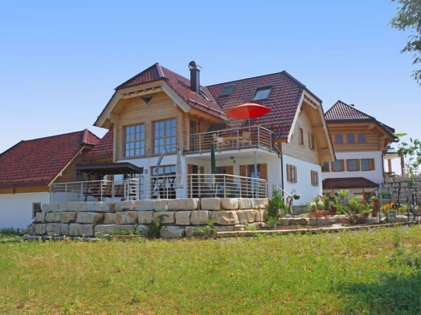 A large, multi-story house with a stone foundation, multiple windows, and a red umbrella. - Apartment Lärche by Interhome (Grosserlach)