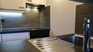 Une cuisine moderne dotée d’un évier en acier inoxydable, d’un four encastré et d’un plan de travail élégant.