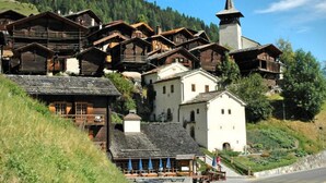 Un village traditionnel en bois, avec des bâtiments de style chalet, une église et un restaurant doté d’une terrasse.