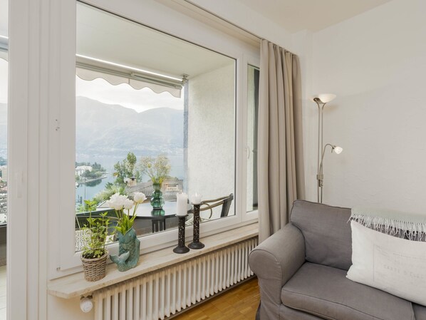 A living room with a view of a lake and mountains, a sofa, a table with candles, and a lamp.