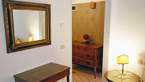 A room with a wooden table, a dresser, a mirror, and a table lamp.