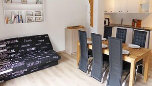A modern living room with a sofa, dining table, and chairs. There is a kitchen area with cabinets and a microwave. - La Borgia A, B, C by Interhome (Les Contamines)
