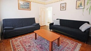 A living room with two dark sofas, a wooden coffee table, patterned rugs, and framed artwork on the walls. - La Busa by Interhome (Alleghe)