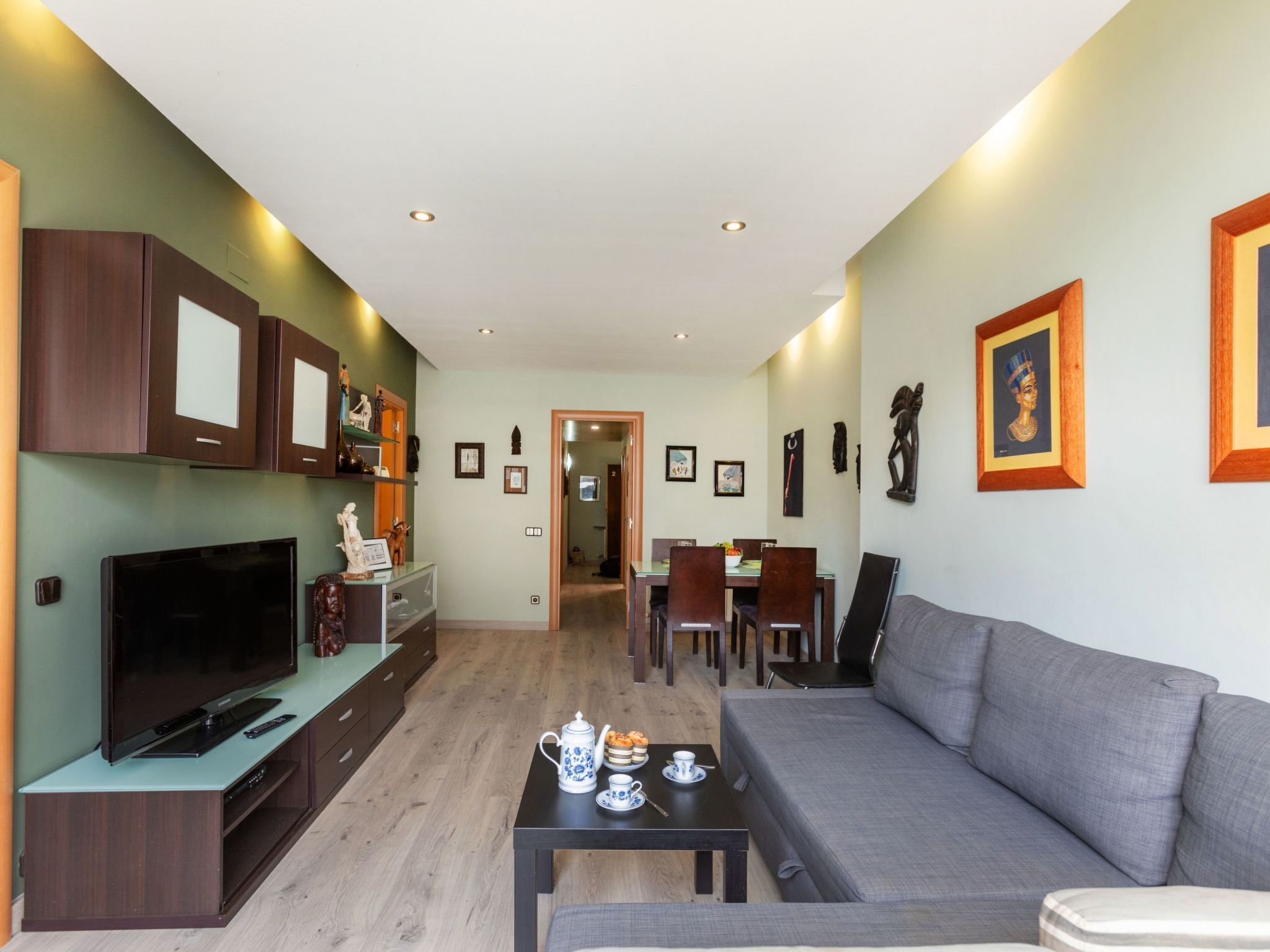Un salon moderne doté d’un téléviseur à écran plat, d’un canapé, d’un coin repas avec des chaises et d’une table basse.