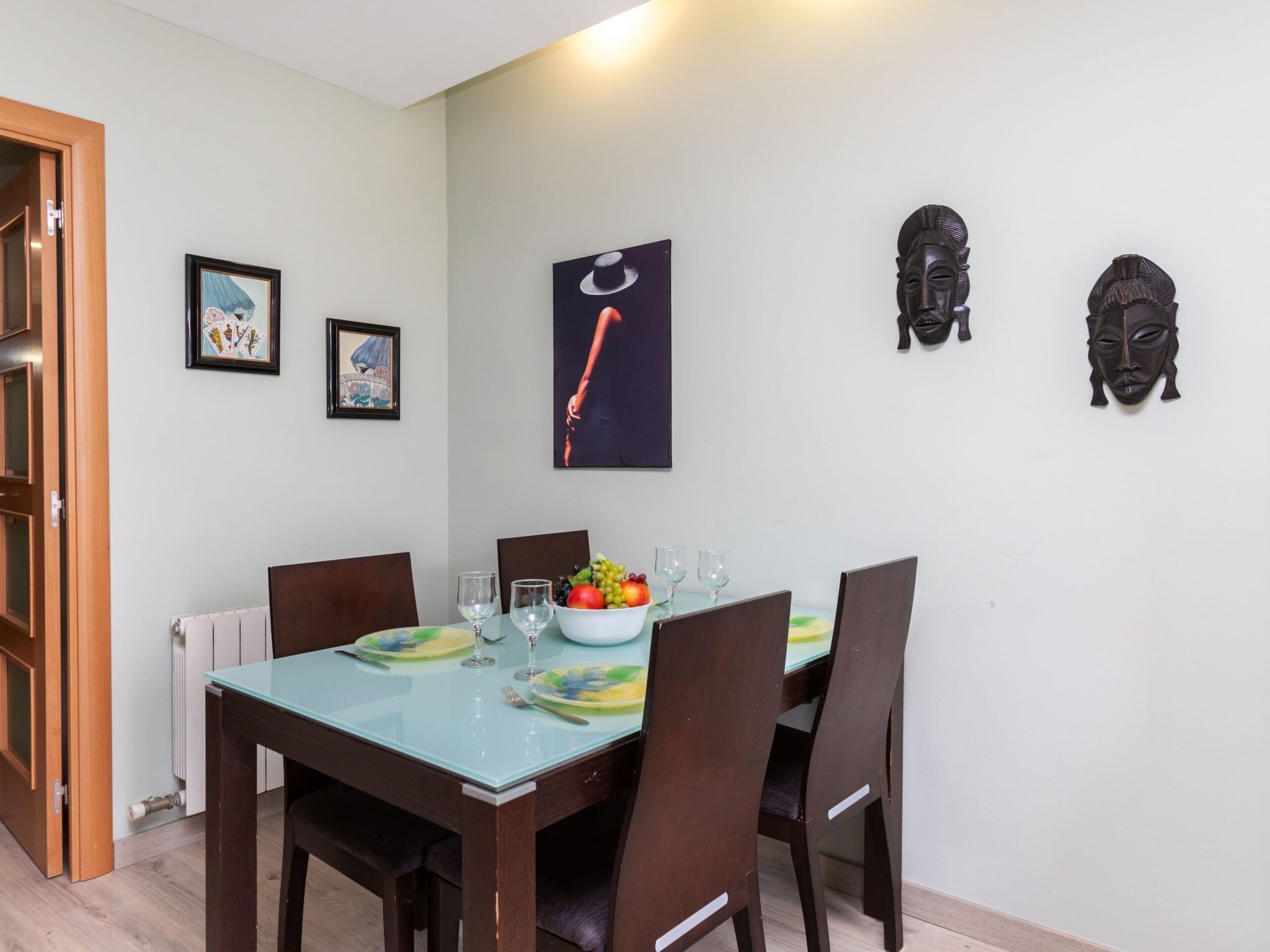Een eethoek met een tafel voor vier personen, kunstwerken aan de muur en een radiator onder de tafel.