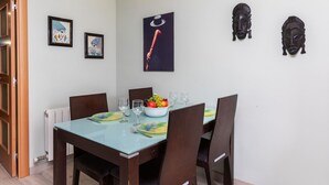 A dining area with a table set for four, framed artwork on the walls, and a radiator below the table.