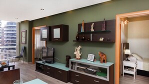 A modern living room with a TV, cabinets, and decorative items on shelves.