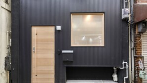 A black exterior wall with a wooden door and a window. - Japan Sessions KANZAKI 01 (Osaka)