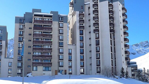 A high-rise residential building with multiple balconies, a modern architectural design, and a snowy landscape in the background. - Les Moutières B1 et B2 (Val Claret) by Interhome (Tignes)