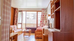 A cozy room with a wooden floor, a bed, a desk, and a window with curtains. - Les Moutières B1 et B2 (Val Claret) by Interhome (Tignes)