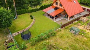 Een groot huis met een rood dak, omgeven door een verzorgd gazon en bomen.
