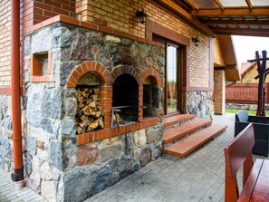Un edificio de piedra con dos hornos de ladrillo, un banco de madera y un patio cubierto.
