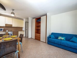 Un appartamento moderno con zona pranzo, angolo cottura e soggiorno con divano blu.