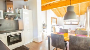 A modern kitchen with white cabinets, a built-in oven, and a dining area with a wooden table and chairs. - Apartment Lanner by Interhome (Axams)