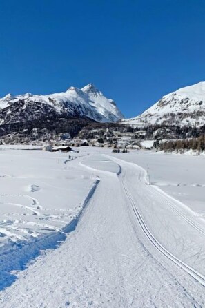 A snow-covered landscape with a winding road leading to a mountain.
