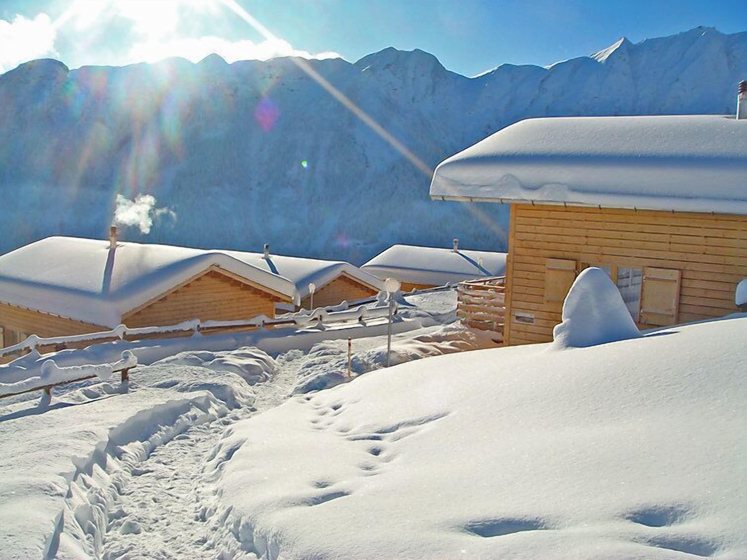 A snow-covered mountain area with wooden cabins.