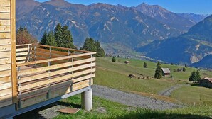 A wooden cabin with a balcony overlooking a mountainous landscape.