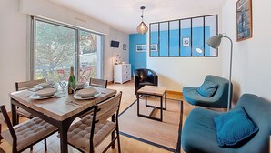 Un coin repas avec une table et des chaises en bois, un canapé et un téléviseur fixé au mur.